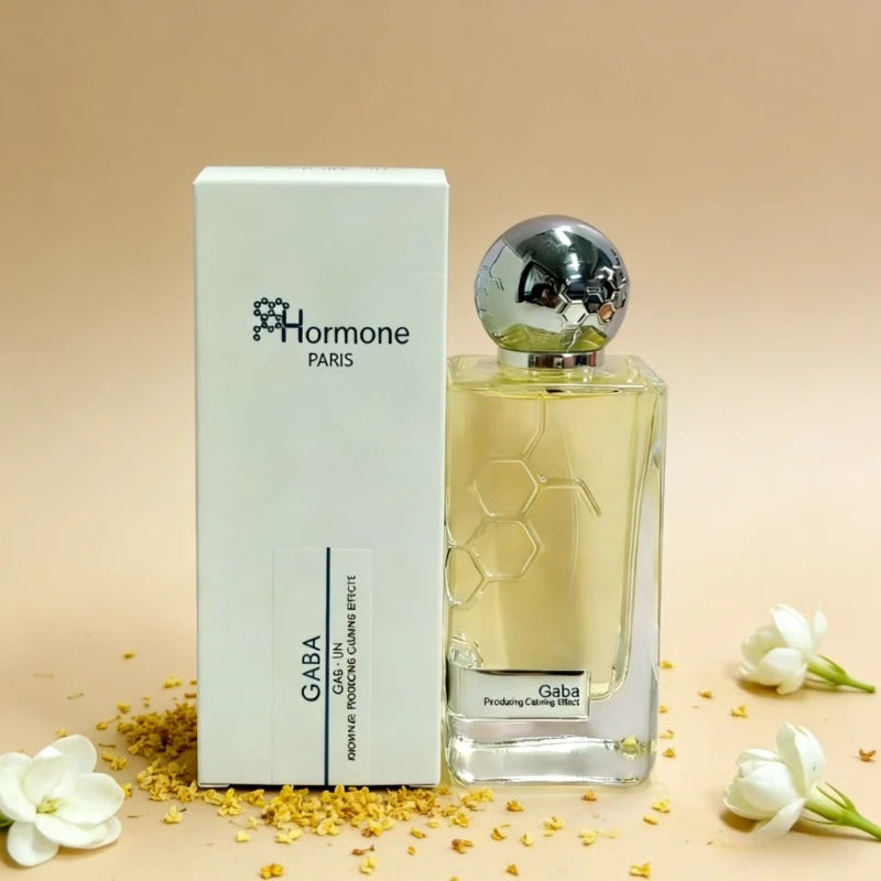 Hormone Paris Gaba perfume bottle and white box, featuring a golden liquid, honeycomb patterns on the bottle and shiny silver cap, with scattered yellow granules and white jasmine flowers