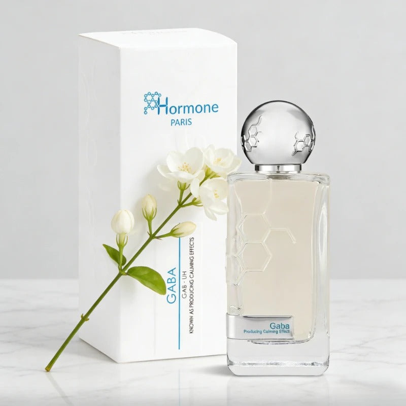 Product photograph of Hormone Paris GABA perfume bottle and white packaging box on a marble surface, featuring a unique silver hexagonal pattern on the cap and etched into the glass, with a sprig of delicate white jasmine flowers